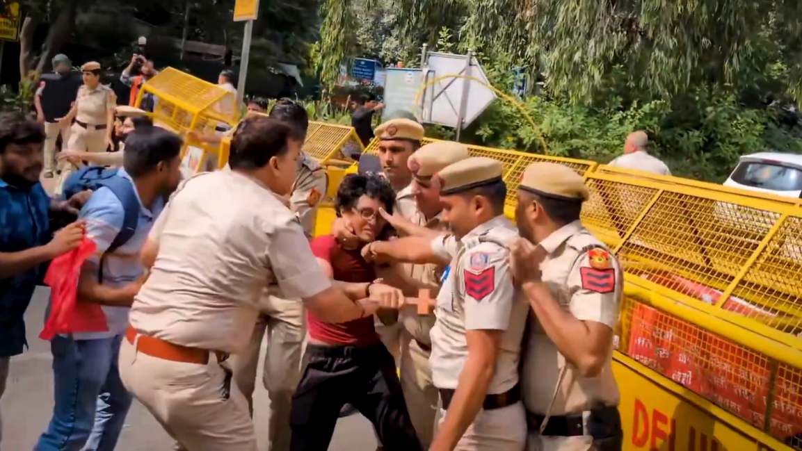 A video grab of police detaining a protester at a barricade near Safdarjung flyover in New Delhi on Saturday.