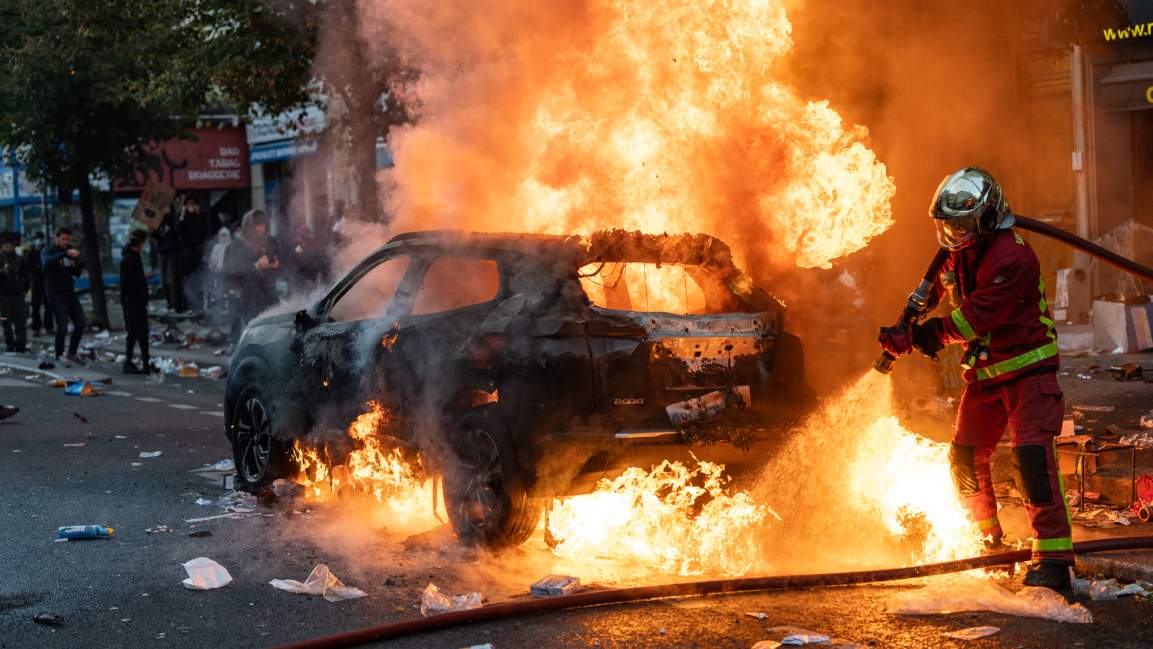 Paris firefighters extinguish a burning car during protests in France